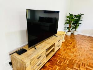 a large flat screen tv on a wooden entertainment center at Birkinshaw Villa ( 3 Bedroom with Parkings ) in Broadview