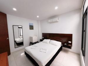 a white bedroom with a bed and a bathroom at Hotel Restaurante Versalles in Melgar +40 photos