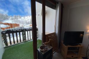 a room with a view of a balcony with a television at 06BP - Beautiful 6-person apartment in Valberg in Valberg