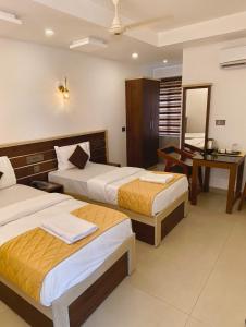 a hotel room with two beds and a desk at PAUL RESIDENCY in Nedumbassery