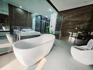 Le Luxe Home - Vinhomes Marina tại Lê Chân في هاي فونج: حمام كبير به ثلاث مغاسل وحوض استحمام