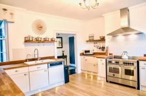 a kitchen with white cabinets and stainless steel appliances at Gleddoch Coach House in Langbank