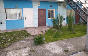 a blue house with red doors and some plants at Departamento equipado Río Grande in Río Grande