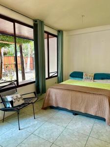 a bedroom with a bed and a chair and windows at Frente la playa Isis in Sámara