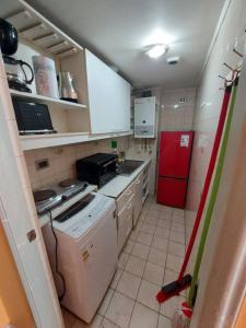 Elle comprend une petite cuisine équipée d'un réfrigérateur rouge et de placards blancs. dans l'établissement Departamento En Centro Turístico De Valparaíso, à Valparaíso