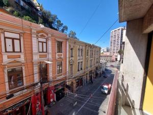 une voiture rouge garée dans une rue à côté des bâtiments dans l'établissement Departamento En Centro Turístico De Valparaíso, à Valparaíso