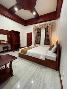 a bedroom with a large bed and a table at PhaiLin Hotel in Luang Prabang