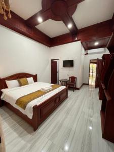 PhaiLin Hotel في لوانغ برابانغ: غرفة نوم بسرير وتلفزيون بشاشة مسطحة