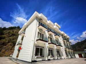 a white building with windows and a blue sky at Hotel Hill River View Resort in Uttarkāshi