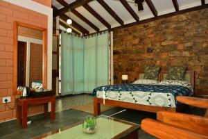 een slaapkamer met een bed en een stenen muur bij Sereno Pool Villa Chikmagalur in Chikmagalūr
