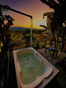a bath tub on a deck with a sunset in the background at Flor del Monte in Sopetran