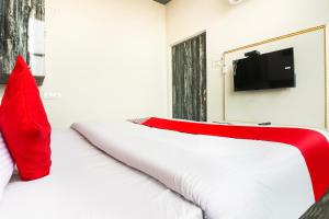Elle comprend un lit blanc avec des oreillers rouges et une télévision à écran plat. dans l'établissement Hotel Sheela, à Rohtak
