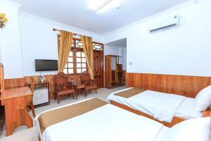 een slaapkamer met 2 bedden, een bureau en een televisie bij Paradis Hotel Quy Nhon in Quy Nhon