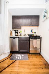 a kitchen with stainless steel appliances and a wooden floor at Renovated, Sunny, Spacious Studio In Boston in Boston