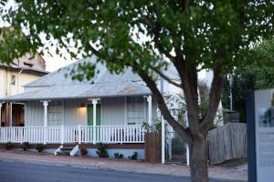 a white house with a porch and a green door at Mill Cottage in Tenterfield