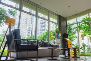 Habitación con sofá, mesa y ventanas. en Flexi-Living Premium Condo in Kasara en Manila