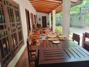 a long wooden table with chairs and food on it at Habarana Dulwan Guest House in Habarana