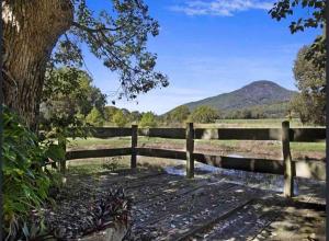 a wooden fence next to a pond in a field at Tiny House Farmstay Mount Warning in Eungella