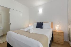 a bedroom with a large white bed with two towels on it at 1 Bedroom ground floor apartment @ Palm Villas in Port Douglas