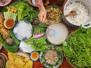 a table filled with plates of food with rice and vegetables at COMFY Riverside Mekong homestay in Ấp Phú Hòa (3)