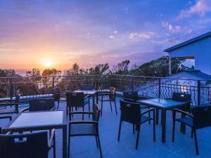 una fila de mesas y sillas en un balcón con vistas a la puesta de sol en HOTEL HOLISTIC RESORT - Vacation STAY 34557v, en Taiji
