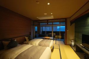 a bedroom with two beds and a flat screen tv at Keishokan Sazanamitei in Fukuyama