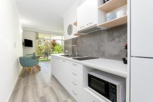 eine weiße Küche mit einer Spüle und einem Kühlschrank in der Unterkunft 1 Bedroom @ Palm Villas #3 in Port Douglas