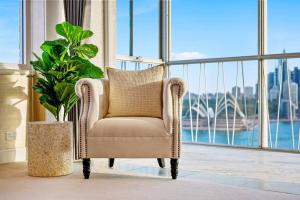 a chair in a room with a potted plant at Sydney's Landmark Views from Luxury 2Bd Apt in Sydney