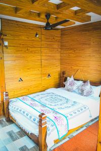 Cama en habitación con pared de madera en Hotel Riverside with Swimming pool, en Sauraha