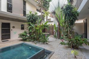 a pool in the courtyard of a building with trees at Habanero Suites & Garden in Playa del Carmen