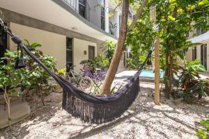 una hamaca atada a un árbol frente a un edificio en Habanero Suites & Garden en Playa del Carmen