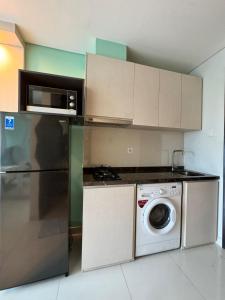 una cucina con frigorifero e lavatrice di Apartemen Puri Mansion Cozy, Lokasi Strategis a Giacarta