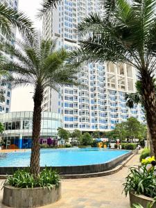 una piscina con palme di fronte a un grande edificio di Apartemen Puri Mansion Cozy, Lokasi Strategis a Giacarta