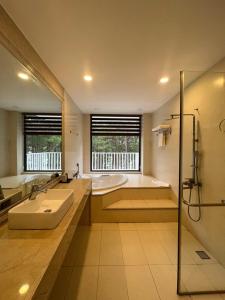 y baño con bañera, lavamanos y ducha. en Romeo & Juliet Dalat Resort en Dalat
