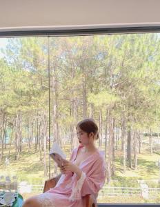 uma mulher sentada numa janela a ler um livro em Romeo & Juliet Dalat Resort em Da Lat