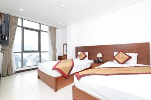 a bedroom with two beds and a large window at Star Hotel and Spa Danang in Danang
