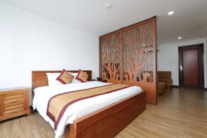 a bedroom with a large bed with a wooden headboard at Star Hotel and Spa Danang in Danang