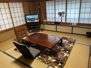 a living room with a table and a television at NEW OPEN『天然温泉』芦ノ湖畔の完全貸切別荘 in Hakone