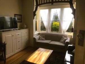 salon z kanapą, telewizorem i oknami w obiekcie Belton Apartments-Hedge Cottage w mieście Hobart