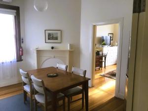 comedor con mesa, sillas y chimenea en Belton Apartments-Hedge Cottage, en Hobart