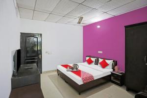 1 dormitorio con cama y pared púrpura en Flagship Hotel Mahi, en Pānīpat
