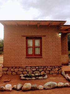 a small brick house with a window and rocks at Amancay Aspha in San Carlos