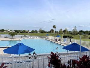 a pool with blue umbrellas and people in it at Stunning Ventura Condo in Orlando