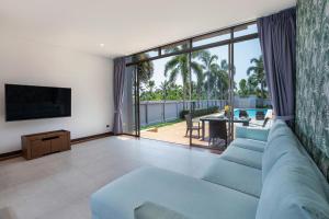 un salon avec un canapé bleu et une télévision dans l'établissement Modern 3BR Pool Access Villa Argent 6, à Ban Muang Mai
