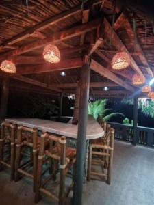 una mesa de madera y sillas bajo un techo con luces en ZenStay Retreats Private Luxury Beach House Rental, en Pandan