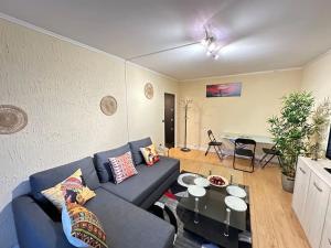 Exotic Spacious Stylish Apartment Retreat في Ris-Orangis: غرفة معيشة مع أريكة زرقاء وطاولة