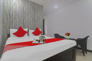 Un dormitorio con una cama con almohadas rojas y una mesa. en Super OYO Alwal Residency, en Hyderabad