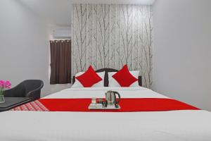 a hotel room with a bed with red pillows at Super OYO Alwal Residency in Hyderabad
