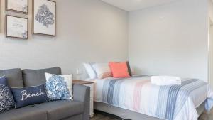 a small bedroom with a bed and a couch at Coasters 18 - steps from downtown Sawtell in Sawtell