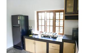 a kitchen with a black refrigerator and a stove at Ronne's Casa De Piscina Privada 3BHK VILLA in Verla